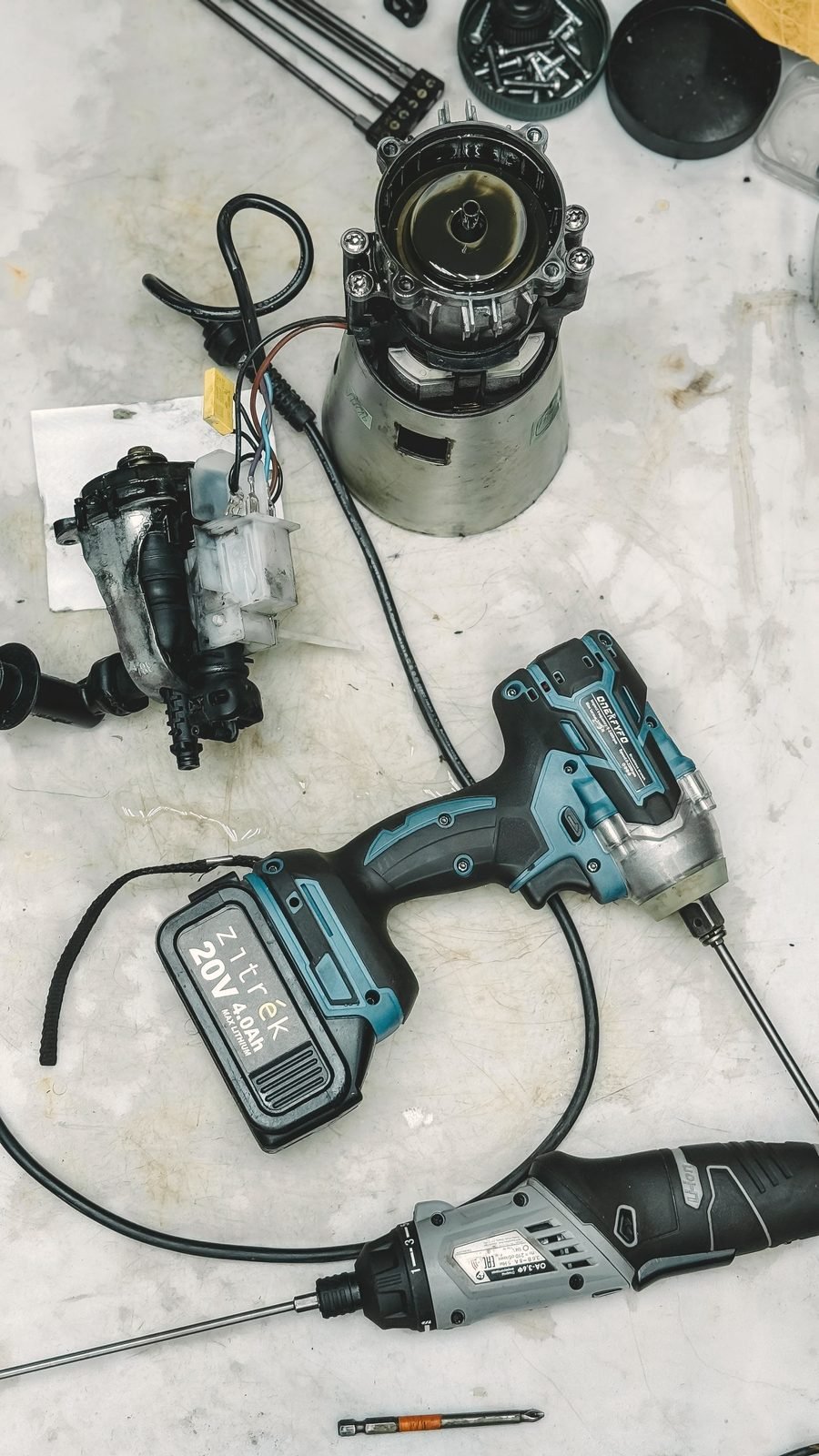 Disassembled appliance parts and a driver laid out on a bench