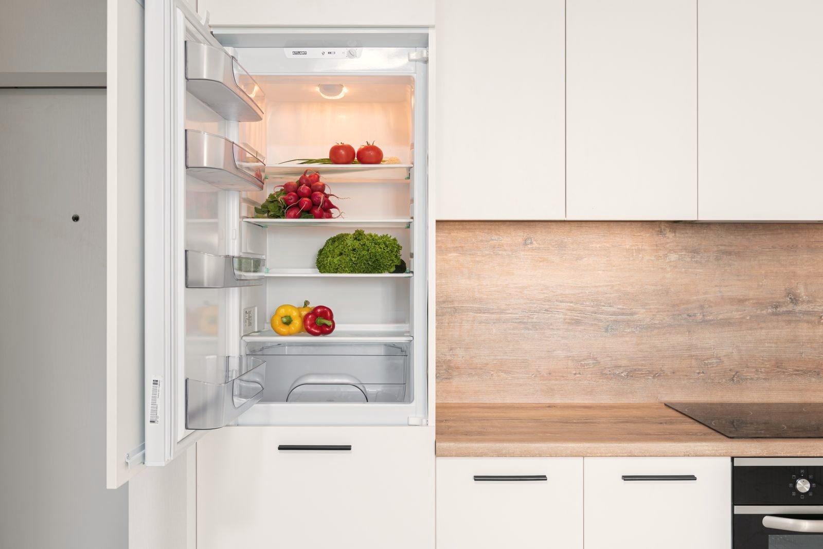 A clean built-in refrigerator standing open in a kitchen