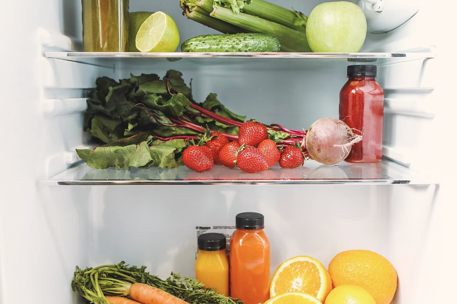 Vegetables and fruit laid across refrigerator shelves