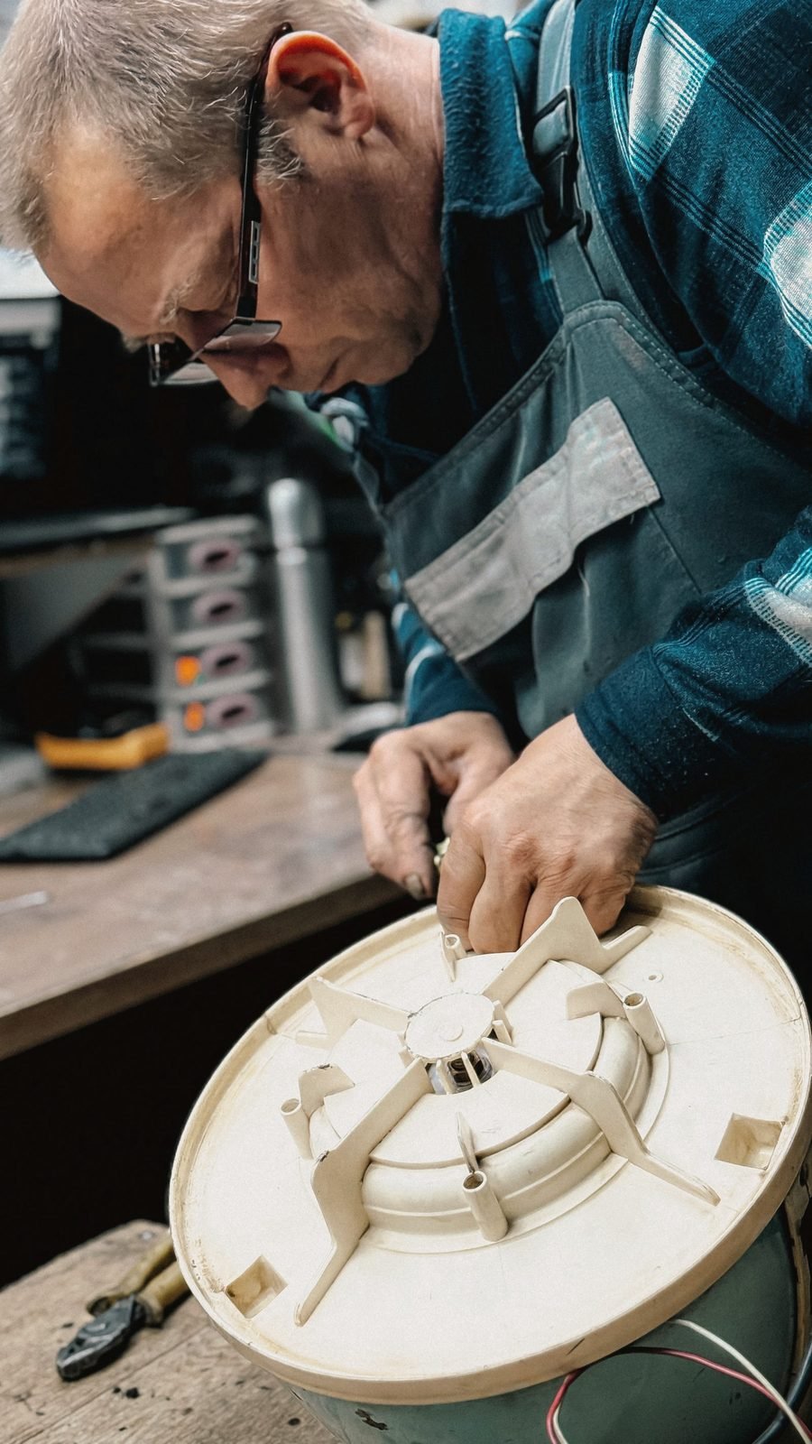 A technician's hands working on an opened appliance component