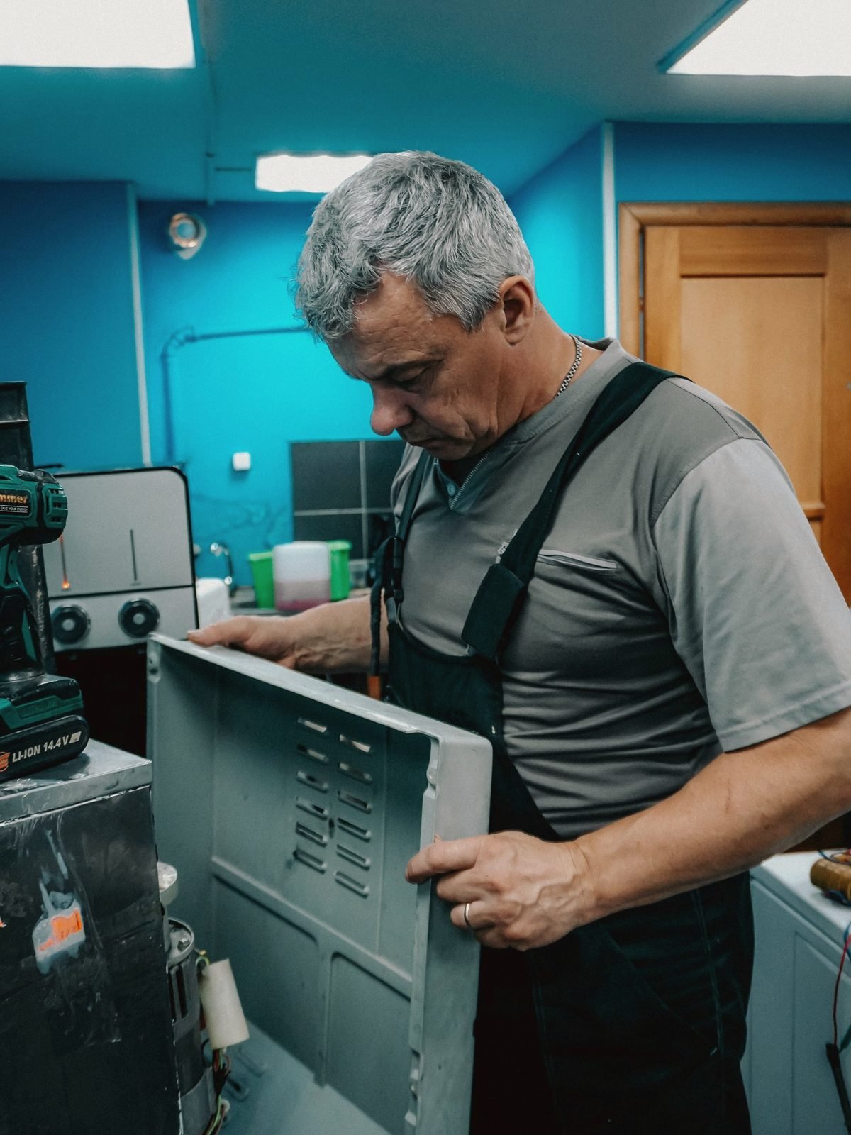 A technician removing the panel from an appliance in a workshop
