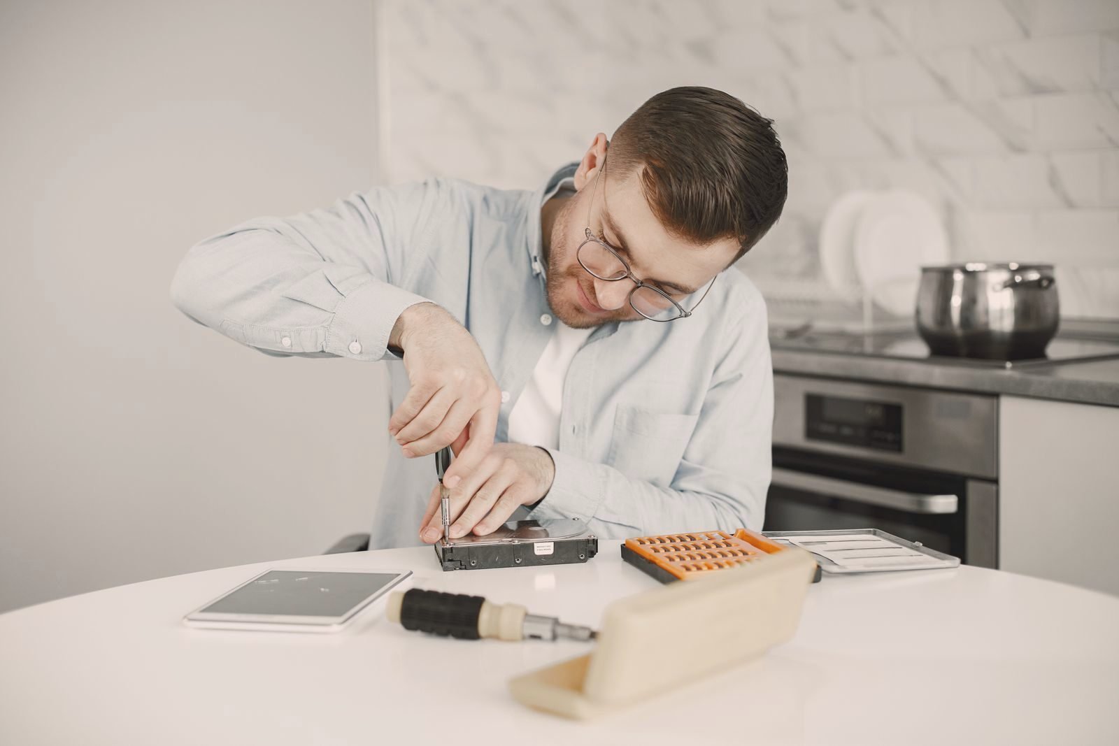 A person repairing an appliance part at a kitchen table